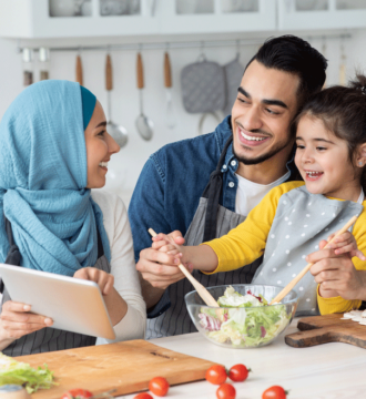Image of a family of 3 cooking and looking at a tablet