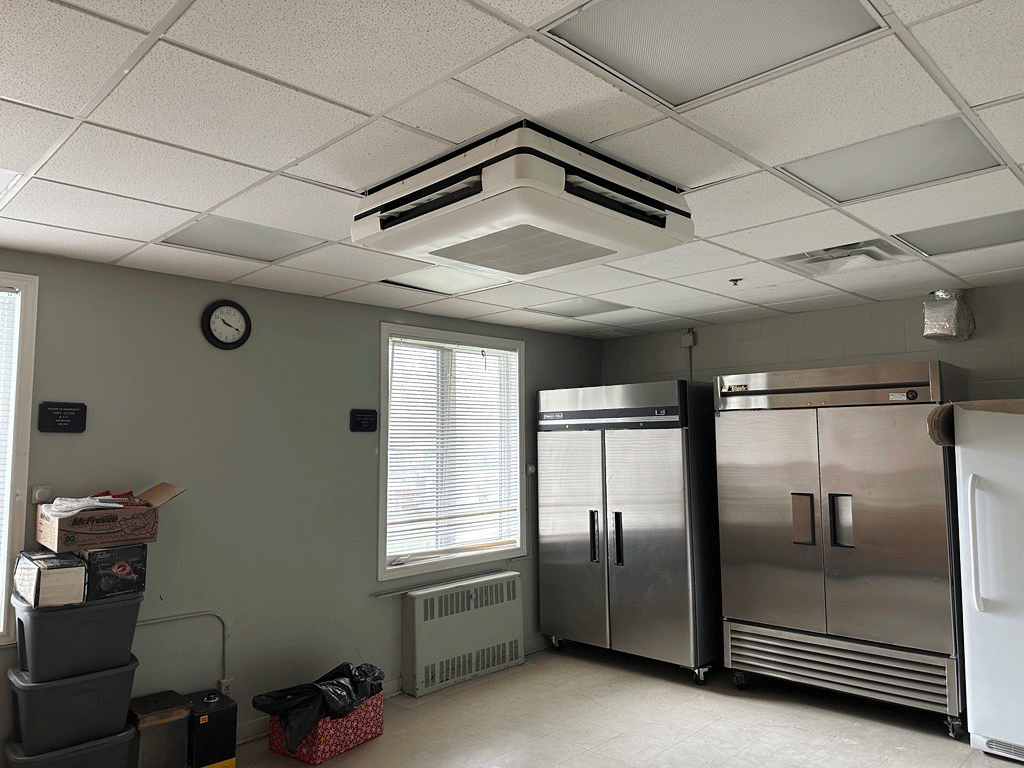 Image of the inside of a room with a low-profile Daikin FXUQ ceiling cassette unit on the ceiling.