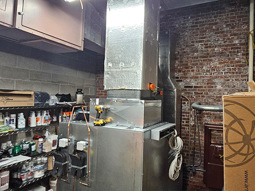 Photo of Side view of a Daikin Preciseline AHU with VRV coil, surrounded by shelves of supplies and exposed brick walls.