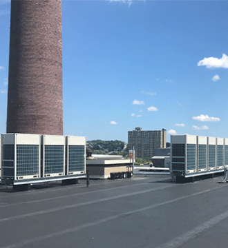 Daikin VRV Units on Rooftop, Bright sky in background.